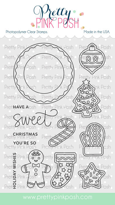 A sheet of Pretty Pink Posh photopolymer clear stamps with Christmas-themed outlines and text, including a wreath, ornament, tree, candy cane, mitten, gingerbread man, stocking, star, and holiday greeting phrases. Pretty Pink Posh Sweet Christmas Cookies Stamp Set