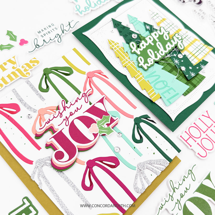 A close-up of layered Christmas greeting cards and decorative paper elements on a white background. The cards feature layered 3D letters spelling 'JOY', palm tree silhouettes, green Christmas trees, bows, holly, and phrases like 'wishing you a Merry Noel' and 'happy Holidays'.