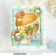 A handmade layered greeting card featuring a large acorn with a colorful confetti-filled window, autumn leaves, two cartoon turkeys, and the words 'Fall Blessings,' shown on a light wood surface with decorative flowers in the background.