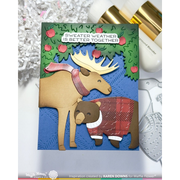A handmade greeting card featuring a moose and a bear in winter sweaters under a green tree with red apples, with the text 'SWEATER WEATHER IS BETTER TOGETHER'. The card is displayed on a white surface with craft tools and paper shaker props.