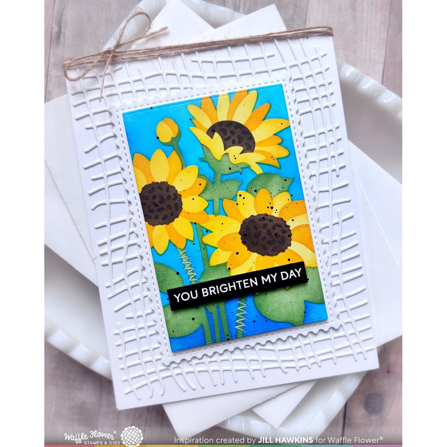 A handmade greeting card featuring a bright sunflower design on a blue background, mounted on a white embossed square card with twine at the top. The card reads 'YOU BRIGHTEN MY DAY' in white text on a black banner.