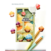 A handmade-style mini slimline card with a window pane design, decorated with colorful cupcake illustrations and a glittery heart balloon reading 'Happy Birthday.' The card is shown on a white background with makeup brushes nearby and text indicating Mini-Slimline (3.