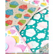 A close-up of cupcake-themed handmade background cardstock for a handmade card with colorful frosting designs on a teal, pink, and beige background.