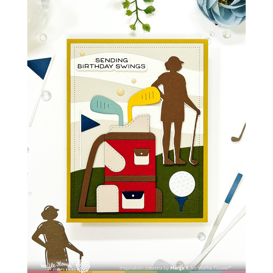 A handmade layered card with a golf theme, featuring a red and brown golf bag, a golfer silhouette, golf clubs, a golf ball, and the text 'SENDING BIRTHDAY SWINGS'. The card is displayed on a white background with small decorative golf props.
