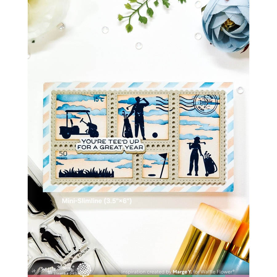 A rectangular mini-slimline card featuring golf-themed postage stamp designs with silhouettes of golfers, a golf cart, and golf clubs on a blue and white striped background. The card is displayed on a white surface with craft tools and flowers around it.