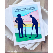 A handmade greeting card with a white border and golf-themed artwork, placed on top of white envelopes on a wooden surface. The card shows two black silhouettes of golfers on a pastel rainbow background with the text, 'WISHING YOU ALL THE BEST IN YOUR NEXT ADVENTURE.