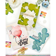 Three handmade greeting cards arranged on a white background with decorative flowers, confetti, and paintbrushes. The cards feature balloon designs in green, pink, and blue, with one card reading 'It's your Day!' and another reading 'HAPPY BIRTHDAY!'.