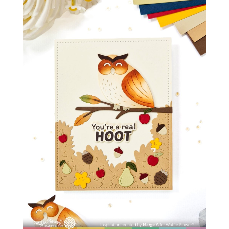 A handmade greeting card featuring a layered owl design perched on a branch with the text 'You're a real Hoot'. The card is styled on a white background with autumn-themed craft elements and a small owl illustration at the bottom.