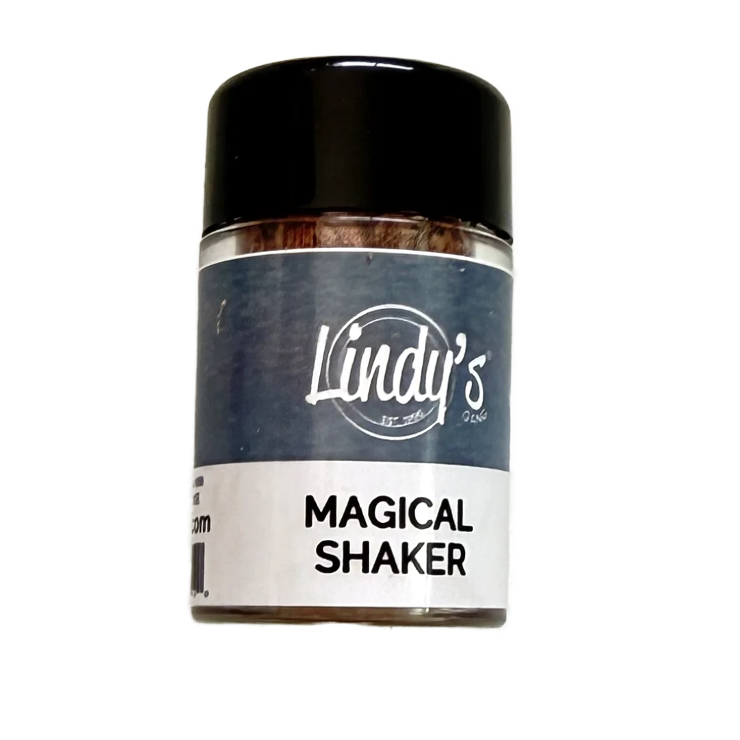 A small clear jar with a black lid and a navy-and-white label reading 'Lindy's' and 'Magical Shaker' on a plain white background. Lindy's Gang Wicked Witch of the Woods by Katie Pertiet Magical Shaker