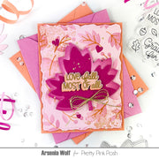 A handmade layered card featuring autumn leaf designs in shades of pink, magenta, and orange, with a gold-foiled 'LOVE fall MOST OF all' sentiment and a small gold bow. The card is displayed on top of matching pink and orange envelopes on a white background decorated with craft elements.