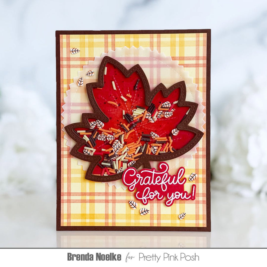 A handmade autumn-themed greeting card featuring a layered red maple leaf with candy and glitter details, set against a yellow and orange plaid background with the text 'Grateful for you!'.